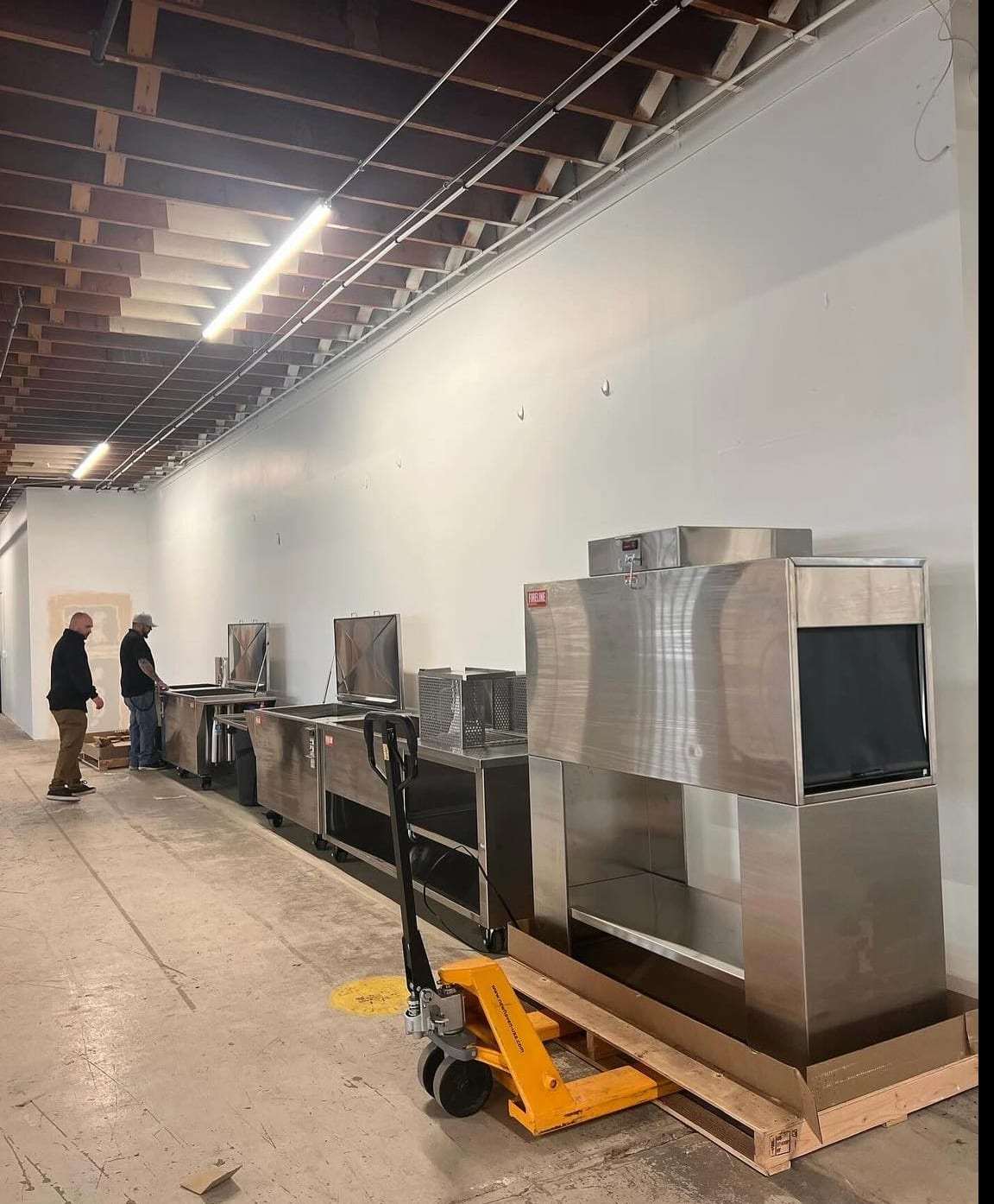 Stainless commercial kitchen equipment being moved into place