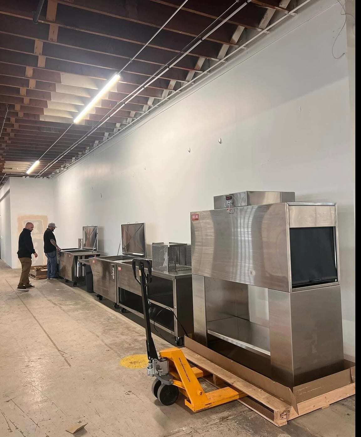 Stainless commercial kitchen equipment being moved into place