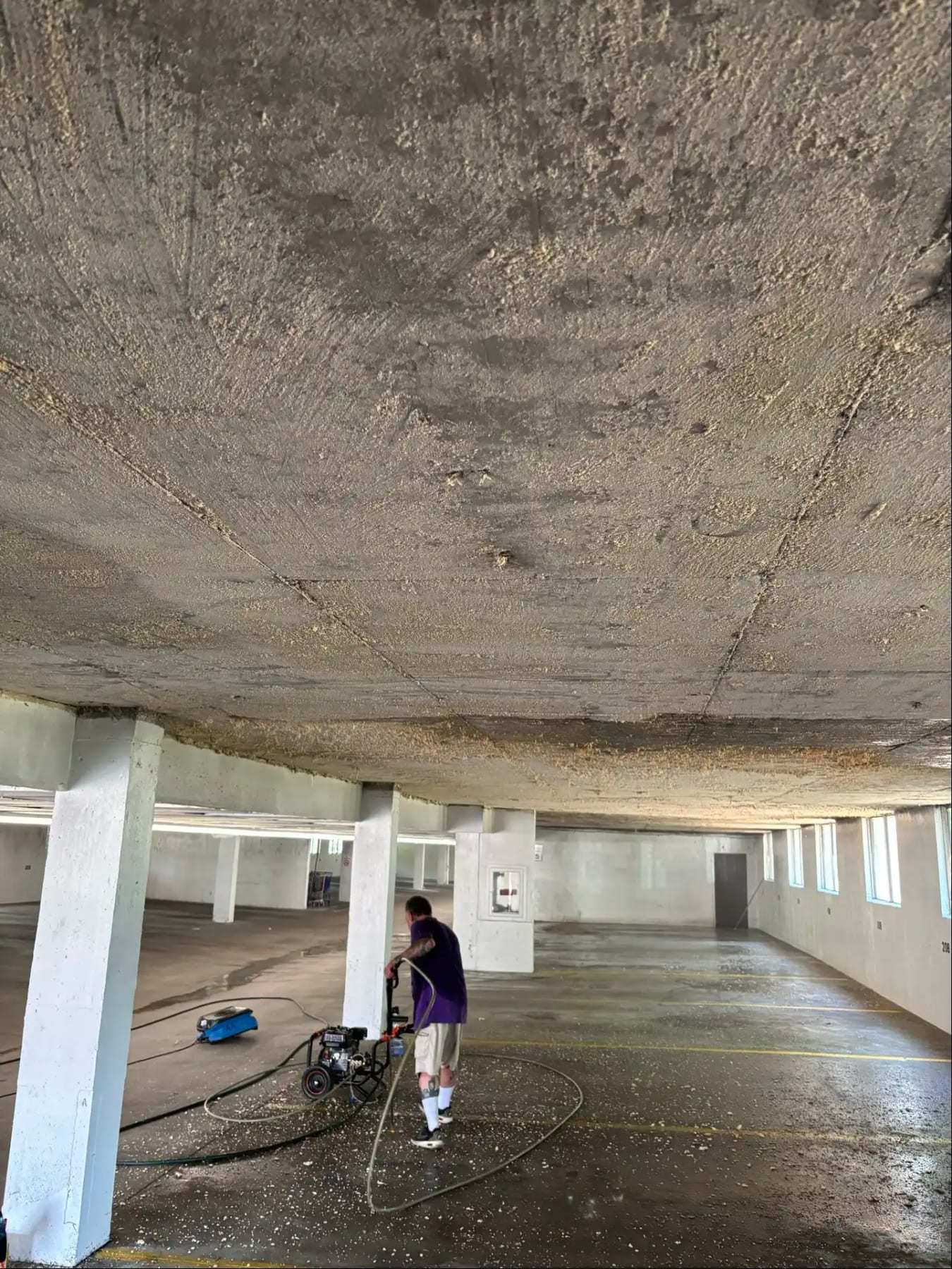 Worker pressure washing the floor of a parking garage